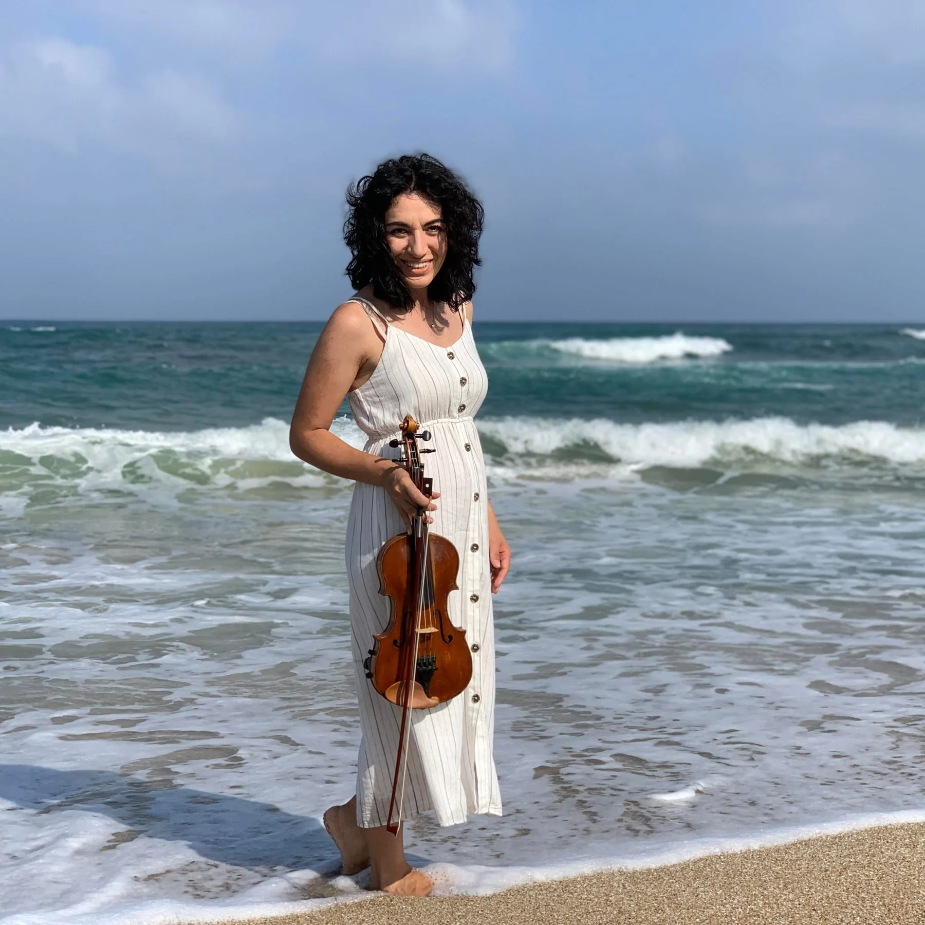 Nelli with violin by the sea